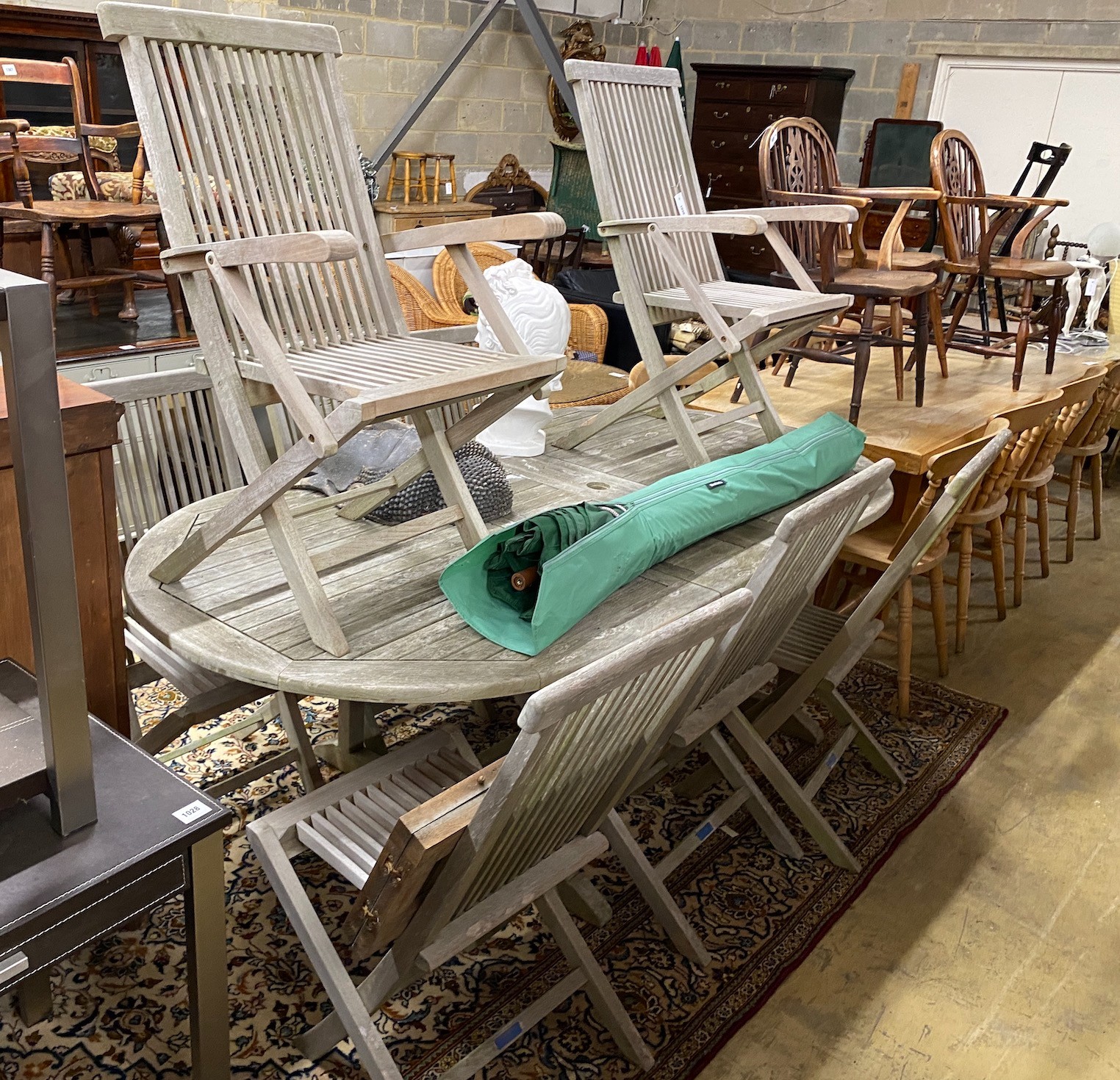 A Lindsey teak garden table with eight chairs and a parasol